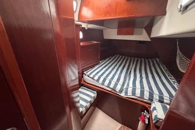 Slide: The Image of Cozy cabin interior of 1996 Beneteau 50 sailboat with striped bedding and wooden finish. - 96