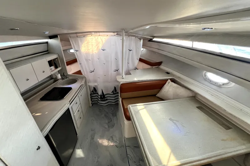 Slide: The Image of 1996 Wellcraft 330 Coastal interior with kitchenette, seating area, and nautical-themed curtain. - 52