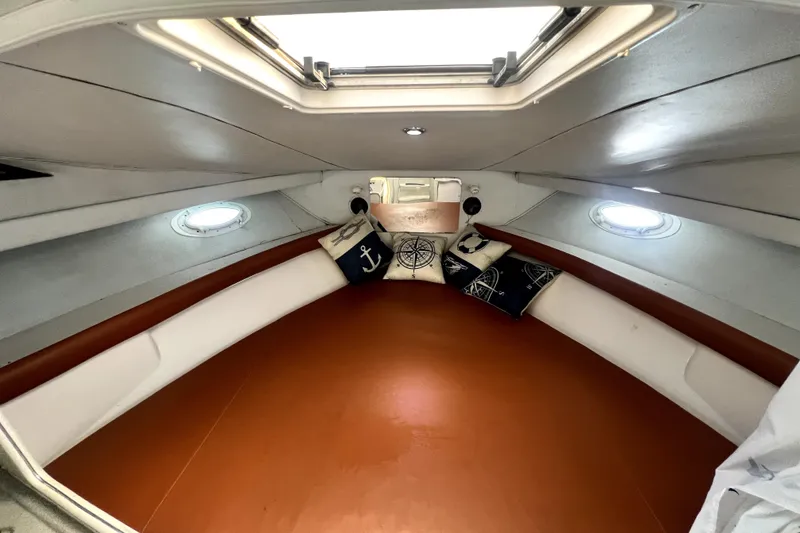 Slide: The Image of 1996 Wellcraft 330 Coastal cabin interior with nautical-themed pillows and porthole windows. - 53