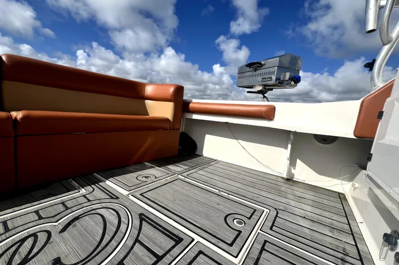 Slide: The Image of 1996 Wellcraft 330 Coastal boat interior with cushioned seating and patterned flooring under a cloudy sky. - 26