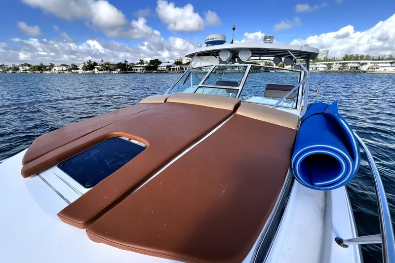 Slide: The Image of 1996 Wellcraft 330 Coastal boat with brown deck cushions and blue mat on calm water. - 41