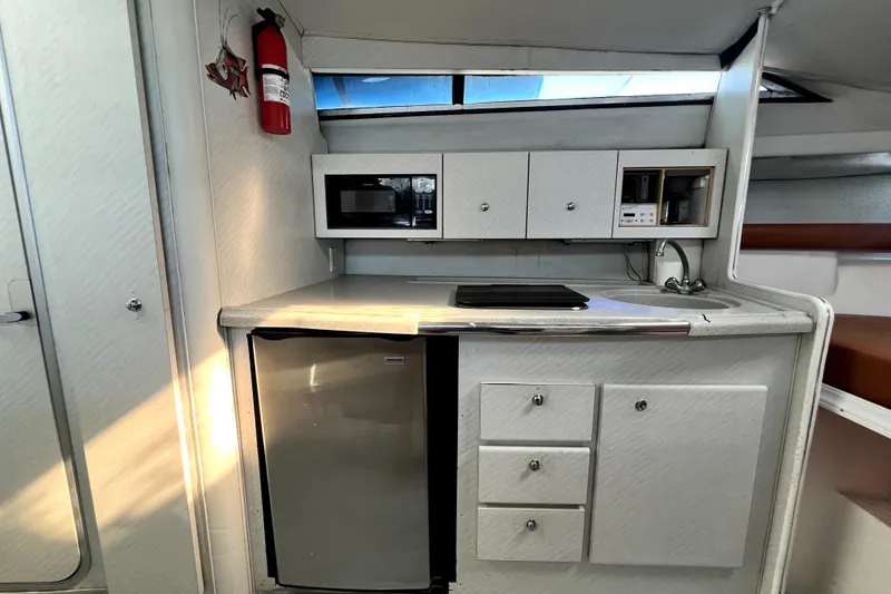 Slide: The Image of 1996 Wellcraft 330 Coastal boat kitchen with microwave, fridge, and cabinets. - 51