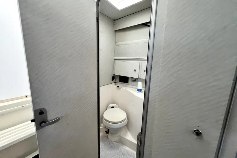 Slide: The Image of 1996 Wellcraft 330 Coastal boat bathroom interior with toilet and storage cabinets. - 55