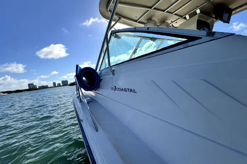 Slide: The Image of 1996 Wellcraft 330 Coastal boat on water, sunny day, city skyline in background. - 27