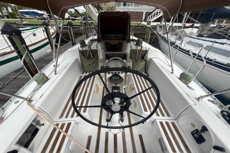 Slide: The Image of The cockpit of a 1990 Beneteau First 35s5 with a large steering wheel and wooden flooring. - 10