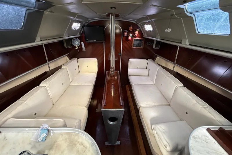 Slide: The Image of Interior of 1990 Beneteau First 35s5 yacht with white seating and wooden accents. - 84