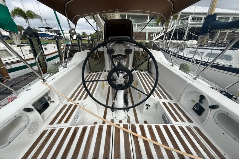 Slide: The Image of The cockpit of a 1990 Beneteau First 35s5 with a large steering wheel and wooden decks. - 6
