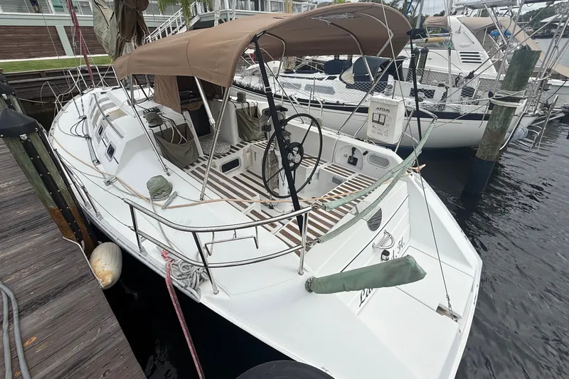 Slide: The Image of A 1990 Beneteau First 35s5 sailboat docked. It features a beige sunshade. - 4