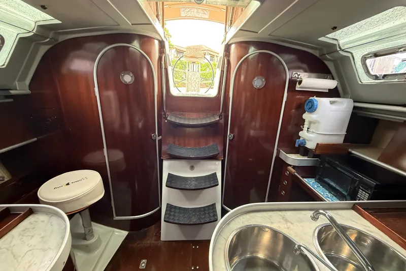 Slide: The Image of Interior of 1990 Beneteau First 35s5 sailboat with wood finish and compact kitchen area. - 100