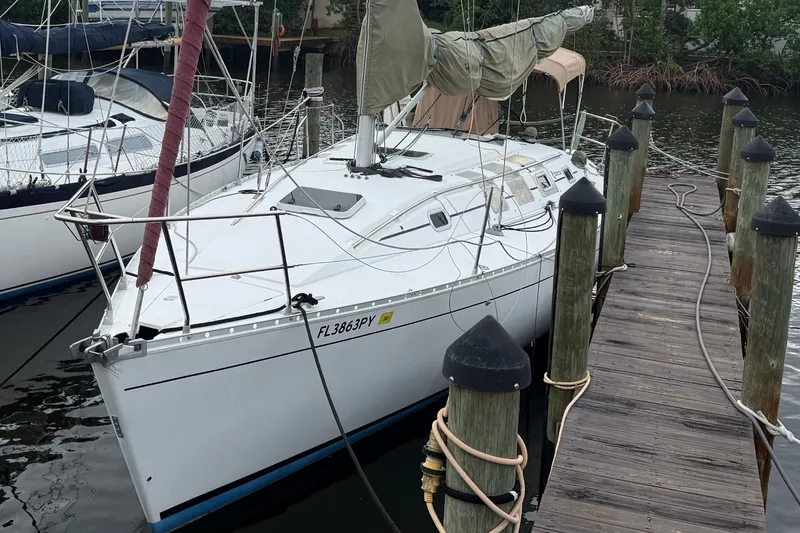 Slide: The Image of A 1990 Beneteau First 35s5 sailboat docked at a wooden pier in a calm harbor. - 2