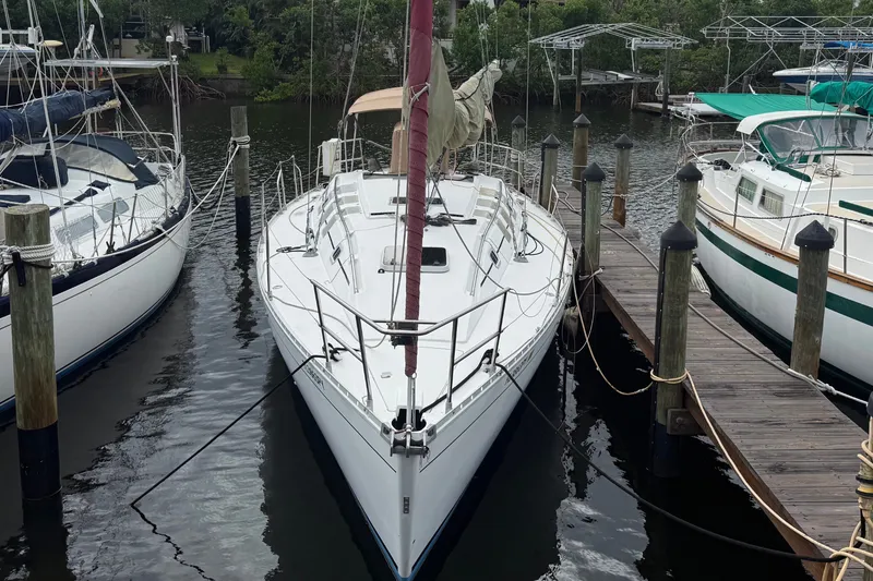 Slide: The Image of A 1990 Beneteau First 35s5 sailboat docked, featuring a red sail and sleek design. - 1