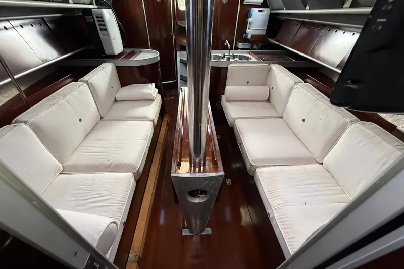 Slide: The Image of Interior of 1990 Beneteau First 35s5 yacht with white cushioned seating and wooden finishes. - 97