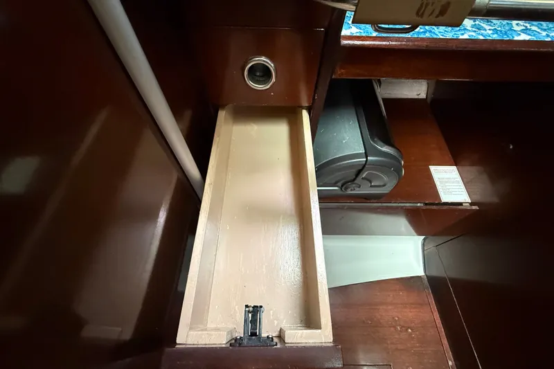 Slide: The Image of Interior view of a 1990 Beneteau First 35s5 sailboat showing a wooden drawer and storage area. - 58