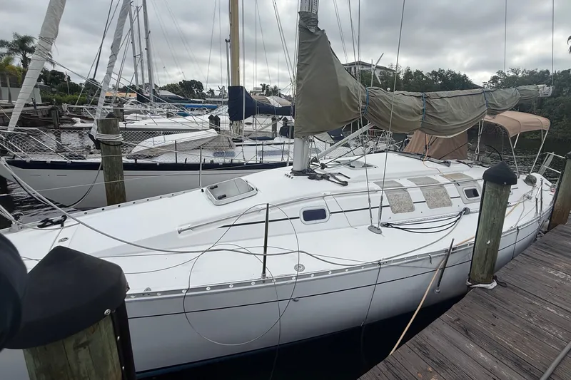 Slide: The Image of A 1990 Beneteau First 35s5 sailboat is docked at a wooden pier. It features a white deck and sails. - 3