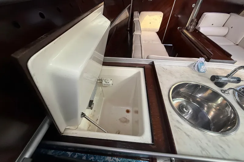 Slide: The Image of Interior of 1990 Beneteau First 35s5 yacht, featuring a compact kitchen with sink and storage. - 69