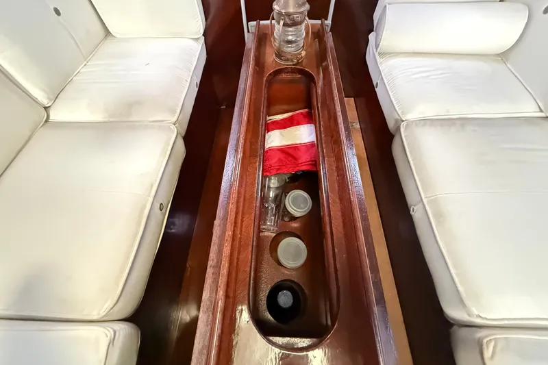 Slide: The Image of Interior of 1990 Beneteau First 35s5 yacht with white seating and wooden storage compartment. - 86