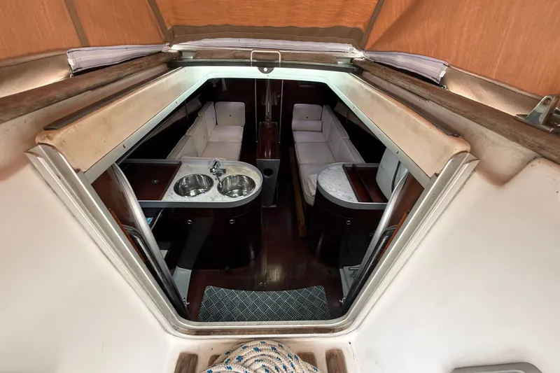 Slide: The Image of Interior of 1990 Beneteau First 35s5 yacht, featuring a compact kitchen and seating area. - 52