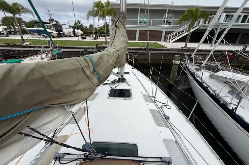 Slide: The Image of 1990 Beneteau First 35s5 sailboat docked, featuring covered mast and deck view. - 26