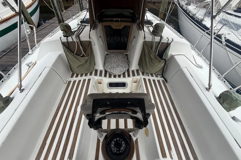 Slide: The Image of The cockpit of a 1990 Beneteau First 35s5 with wooden flooring and a steering wheel. - 13