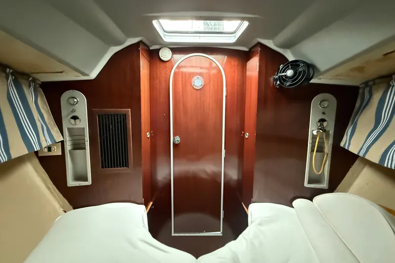 Slide: The Image of Interior cabin of 1990 Beneteau First 35s5 sailboat with wood paneling and striped curtains. - 94