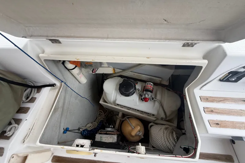 Slide: The Image of Open storage compartment on a 1990 Beneteau First 35s5 sailboat, showing equipment and ropes. - 16