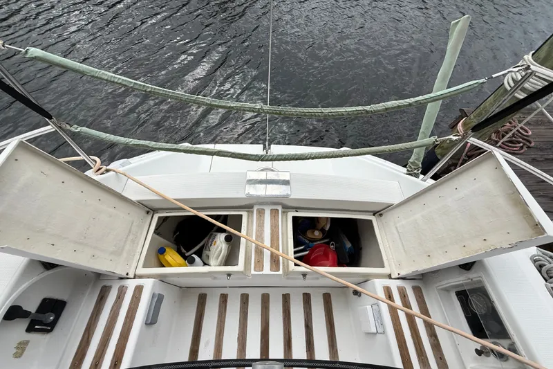 Slide: The Image of Beneteau First 35s5 sailboat deck with open storage compartments, docked by the water. - 48