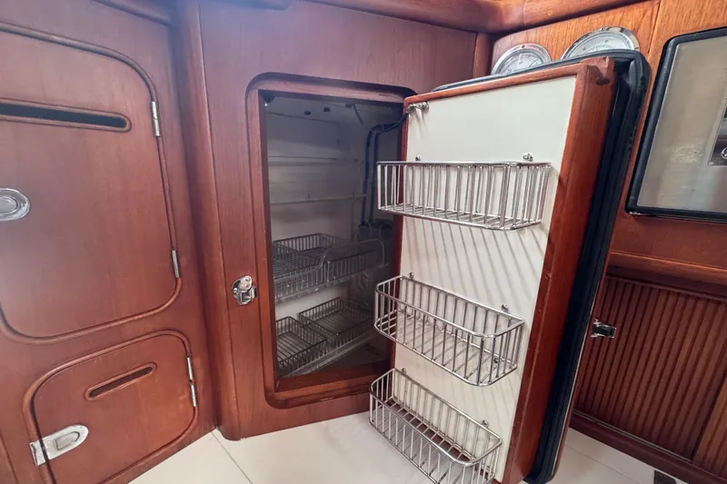 Slide: The Image of Interior of 1989 Little Harbor Sloop 58' with open wooden cabinet and metal storage racks. - 60