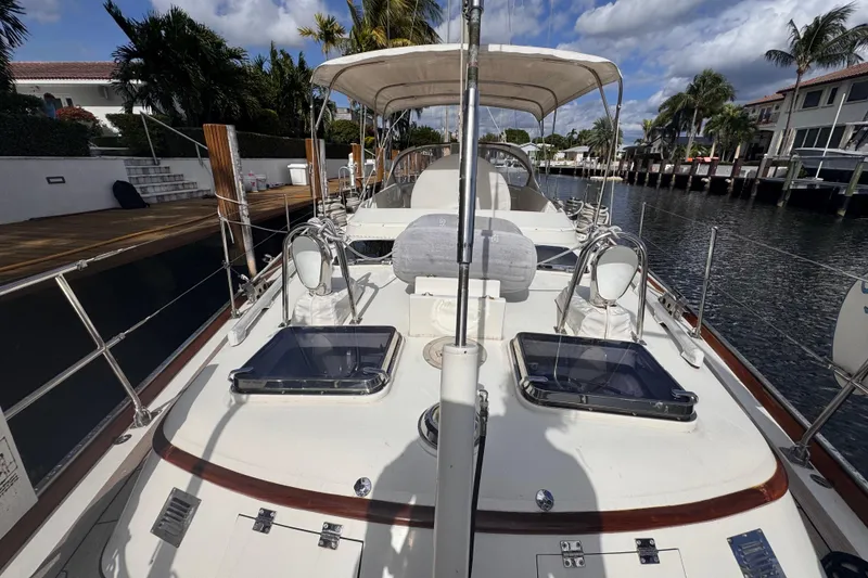 Slide: The Image of 1989 Little Harbor Sloop 58' docked, showcasing deck and canopy under a partly cloudy sky. - 16