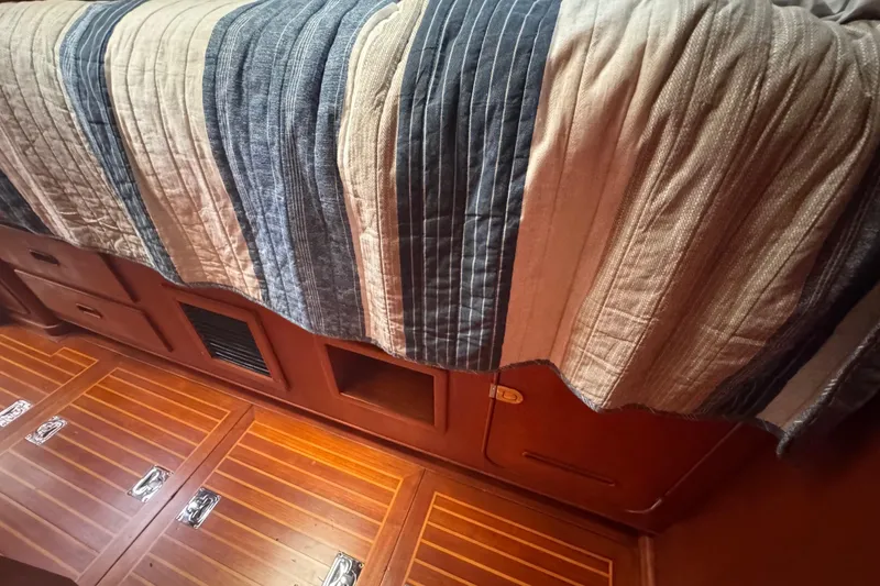 Slide: The Image of Interior of 1989 Little Harbor Sloop, featuring striped bedding and wooden storage compartments. - 77