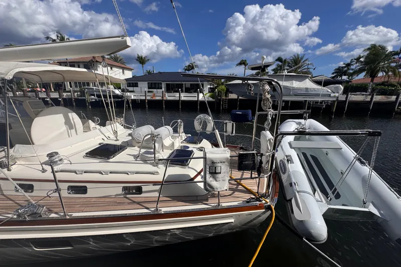 Slide: The Image of 1989 Little Harbor Sloop 58' docked, featuring a spacious deck and inflatable dinghy. - 9