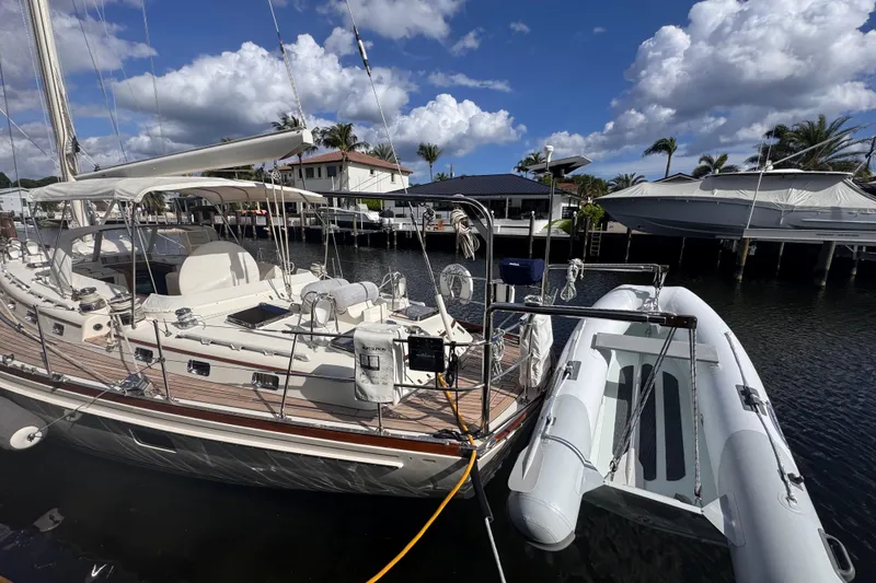 Slide: The Image of 1989 Little Harbor Sloop 58' docked with inflatable dinghy, under a partly cloudy sky. - 8