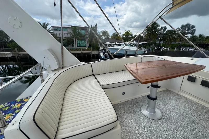 Slide: The Image of 1989 Ocean Yachts 48 Motor Yacht with outdoor seating and wooden table, docked by waterfront homes. - 107