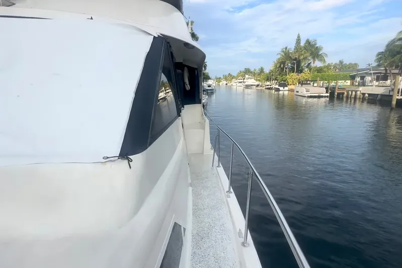 Slide: The Image of Die Ocean Yachts 48 Motor Yacht von 1989 fährt entlang eines ruhigen Kanals mit Palmen am Ufer. - 10