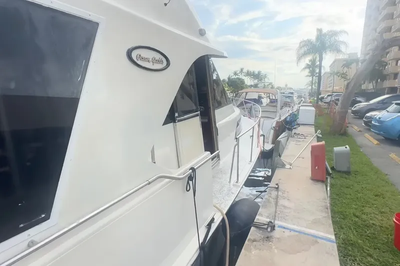 Slide: The Image of Eine weiße Yacht von Ocean Yachts liegt an einem Dock, umgeben von anderen Booten und Palmen. - 4