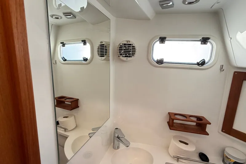 Slide: The Image of 2024 Targa 37 yacht bathroom with modern fixtures, mirror, and porthole windows. - 50
