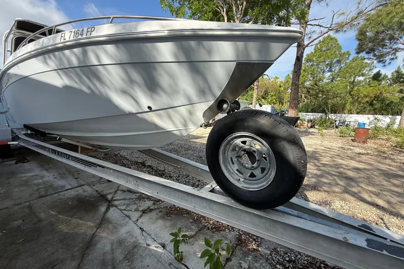 Slide: The Image of 1989 Wellcraft 302 Scarab boat on trailer, parked outdoors with trees in background. - 30