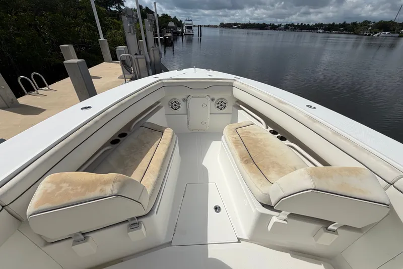 Slide: The Image of 2014 Jupiter 34 FS boat interior with cushioned seating, docked by a calm waterfront. - 60