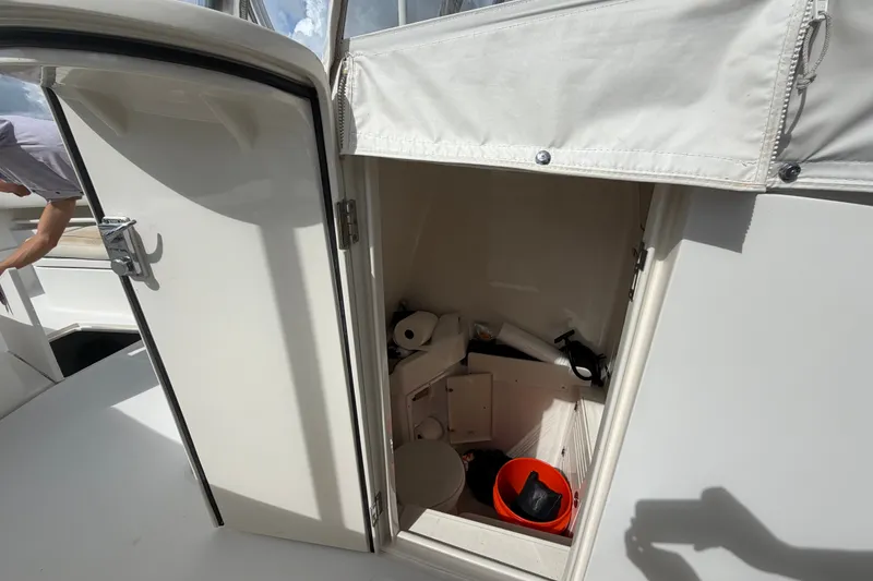Slide: The Image of Open storage compartment on 2014 Jupiter 34 FS boat, containing various items including a bucket. - 54
