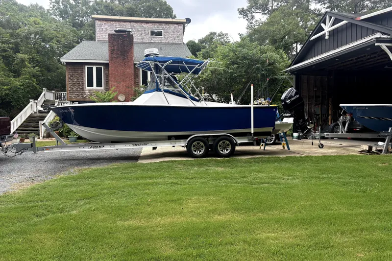 Slide: The Image of 1978 B&D 24 Cuddy boat on trailer, parked near a house and garage. - 1