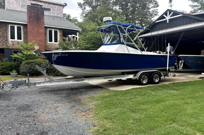 The Image of 1978 B&D 24 Cuddy boat on trailer, parked in driveway near house. - 0