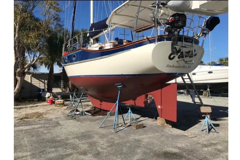 Slide: The Image of A 1978 CSY 37 sailboat is on stands on land. It features a cream hull with blue accents. - 1