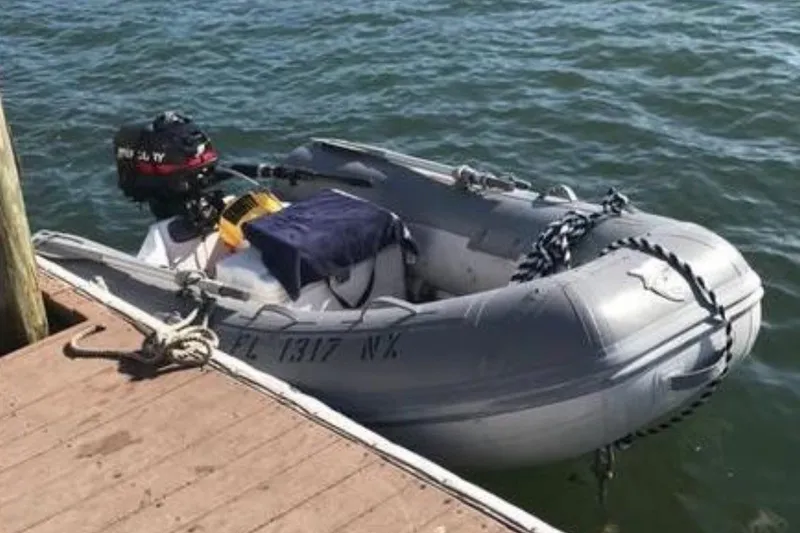 Slide: The Image of A small gray inflatable boat is moored to a wooden dock. It has an outboard motor. - 11