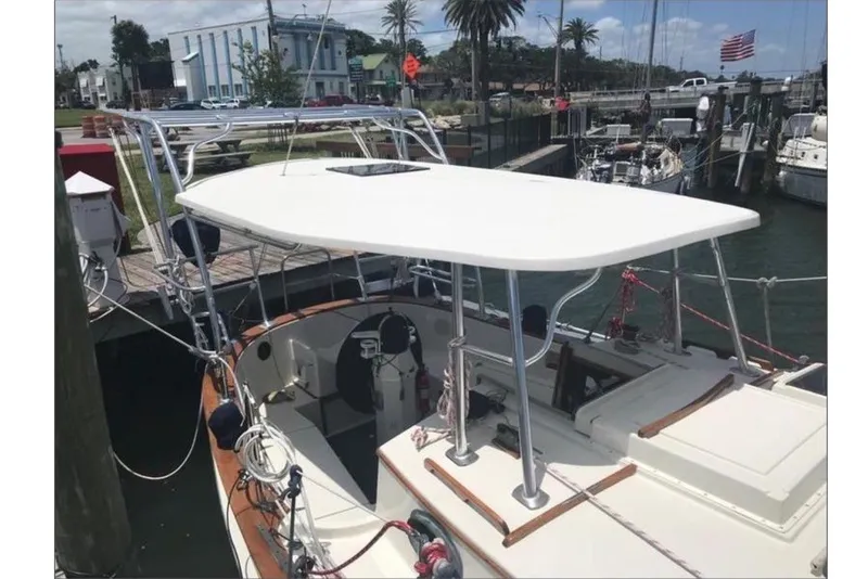 Slide: The Image of A 1978 CSY 37 sailboat docked in a harbor. It features a white deck and sunshade. - 2