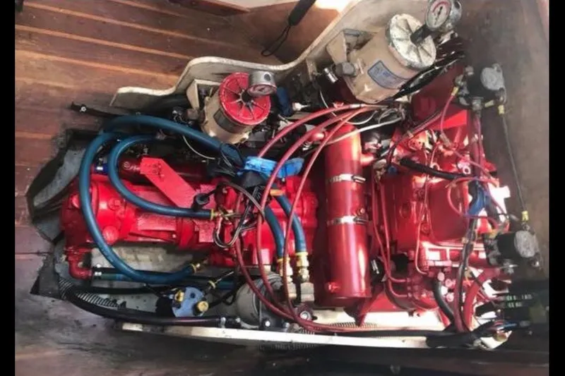 Slide: The Image of A red engine with various hoses and wires is mounted within a wooden frame. - 12