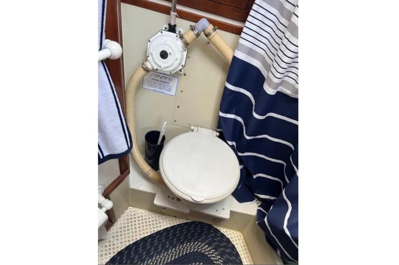 Slide: The Image of The image shows a boat toilet with a white seat and blue-striped curtains. - 9