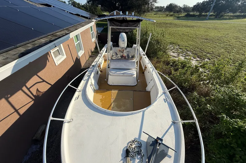 Slide: The Image of 1977 Mako 235 boat parked beside a house with solar panels, surrounded by greenery. - 12