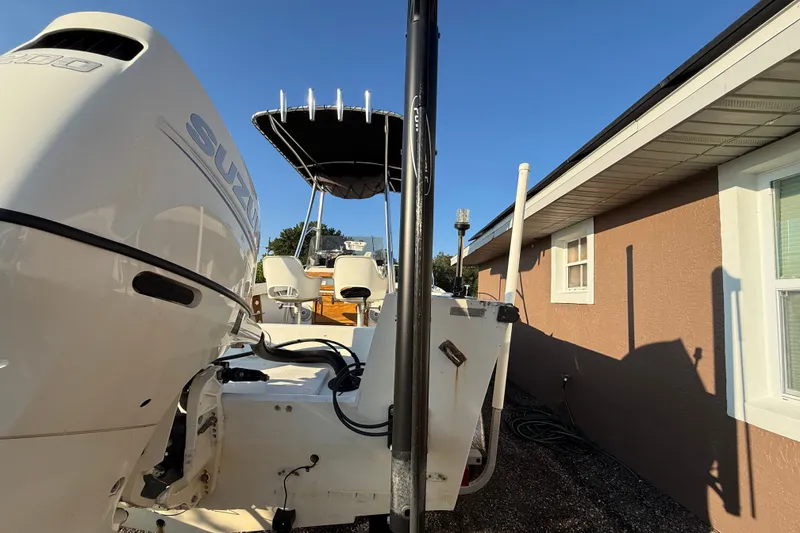 Slide: The Image of 1977 Mako 235 boat with Suzuki engine, parked beside a house under clear blue sky. - 3