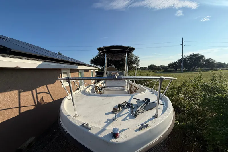 Slide: The Image of 1977 Mako 235 boat docked beside a house, under a clear blue sky. - 11