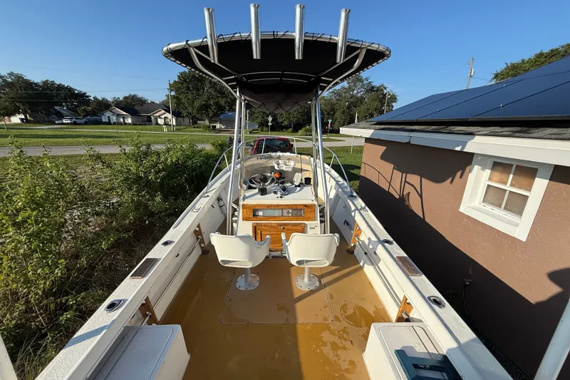 Slide: The Image of 1977 Mako 235 boat with T-top, dual seats, and console, parked beside a house. - 21