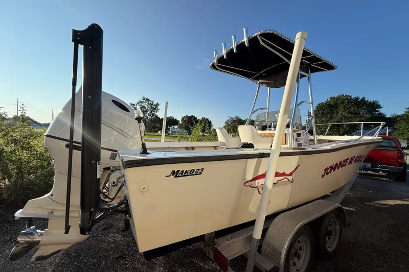 Slide: The Image of 1977 Mako 235 boat on trailer with Suzuki outboard motor, parked outdoors. - 8